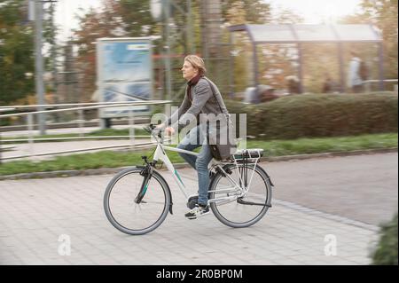 Adolescent à vélo sur la route de terre jusqu'à la gare, Bavière, Allemagne Banque D'Images