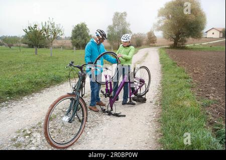 Couple senior roue de réglage du cycle sur route de terre, Bavière, Allemagne Banque D'Images