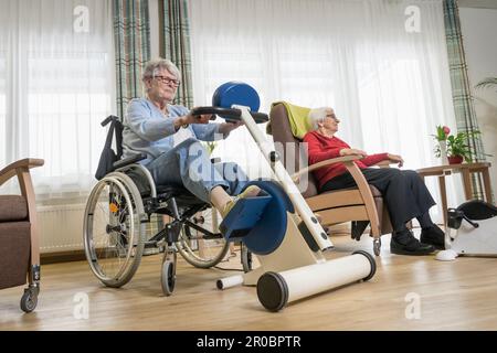 Deux femmes âgées s'exerçant sur un vélo d'exercice dans la maison de repos Banque D'Images