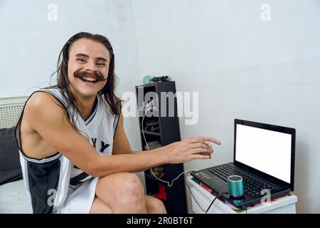 jeune femme non binaire latino personne sur son lit assis dans sa chambre très heureux rire en regardant la caméra tout en utilisant son ordinateur portable, la technologie conc Banque D'Images