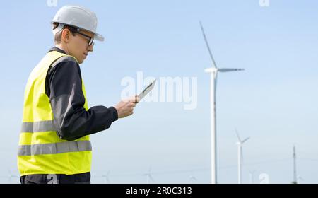 Ingénieur avec une tablette sur un fond d'éoliennes. Photo de haute qualité Banque D'Images