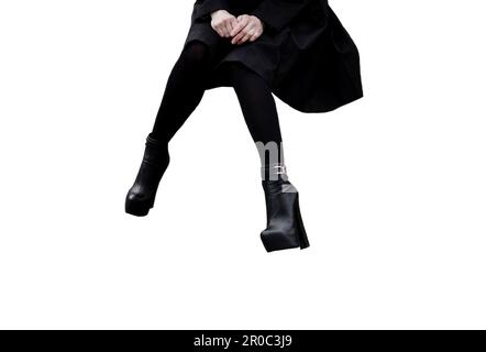 femme en manteau noir et bottes en cuir sur les jambes isolées sur un fond blanc. femme sur les talons hauts Banque D'Images