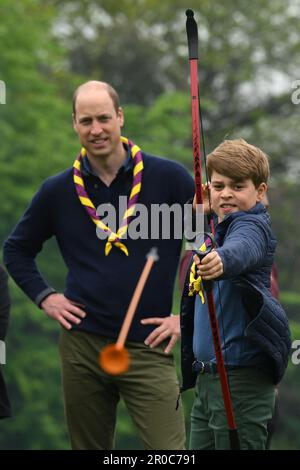 Le Prince George, observé par le Prince de Galles, tente de tir à l'arc tout en se joignant à des bénévoles pour aider à rénover et à améliorer le 3rd Upton Scouts Hut à Slough, dans le cadre de la grande aide, pour marquer le couronnement du roi Charles III et de la reine Camilla. Date de la photo: Lundi 8 mai 2023. Banque D'Images