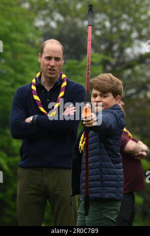 Le Prince George, observé par le Prince de Galles, tente de tir à l'arc tout en se joignant à des bénévoles pour aider à rénover et à améliorer le 3rd Upton Scouts Hut à Slough, dans le cadre de la grande aide, pour marquer le couronnement du roi Charles III et de la reine Camilla. Date de la photo: Lundi 8 mai 2023. Banque D'Images