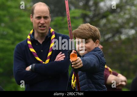 Le Prince George, observé par le Prince de Galles, tente de tir à l'arc tout en se joignant à des bénévoles pour aider à rénover et à améliorer le 3rd Upton Scouts Hut à Slough, dans le cadre de la grande aide, pour marquer le couronnement du roi Charles III et de la reine Camilla. Date de la photo: Lundi 8 mai 2023. Banque D'Images