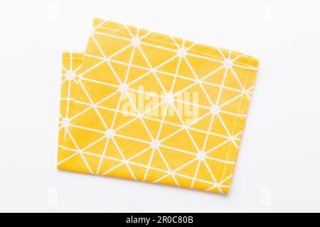 vue de dessus avec serviette de cuisine jaune vide isolée sur fond de table. Tissu plié pour la maquette avec espace de copie, pose à plat. Style minimaliste. Banque D'Images