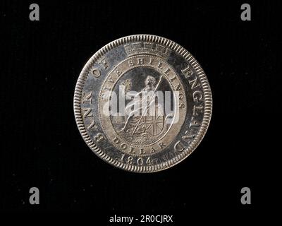 [Marche arrière]. La Banque d'Angleterre a régénéré Britannia Dollar cinq jetons de shilling, 1804. Fabricant : Matthew Boulton, Soho Mint. Fabricant: Soho Mint. Graveur: Conrad Heinrich Küchler.. CONTRE: GEORGIUS III DEI GRATIA REX. Lauréat et buste drapé de George III face à droite avec les cheveux curling sur les deux épaules... Marche arrière :. BANQUE D'ANGLETERRE 1804 Britannia assis à gauche avec lance dans la main gauche et lance de Laurier dans la main droite; avec bouclier ovale, portant les croisements combinés de St. George, St Patrick et St. Andrew, de couleur heraldique. Cornucopia sous bouclier et four en arrière-plan. Tous dans le cadre d'une interdiction ovale Banque D'Images