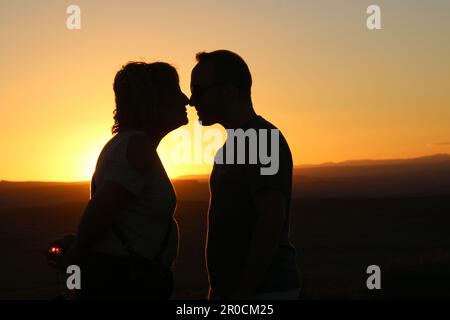 Silhouette d'un couple face à l'autre au coucher du soleil Banque D'Images