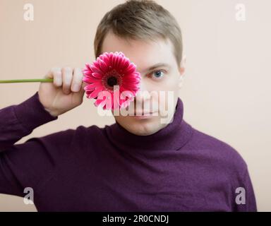 Jeune homme tenir gerbera flower dans la main. Banque D'Images