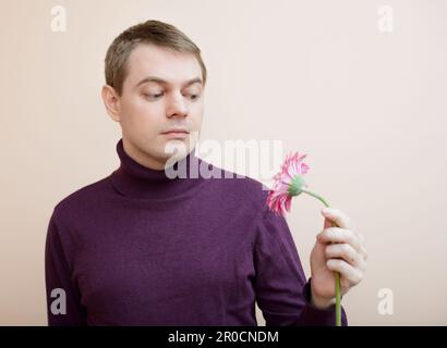 Jeune homme tenir gerbera flower dans la main. Banque D'Images