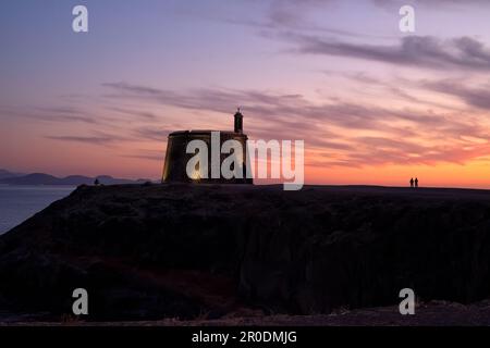 Un Castillo de las Coloradas illuminé ou Torre del Águila près de Playa Blanca, Lanzarote dans les îles Canaries silhoueté contre un beau coucher de soleil Banque D'Images
