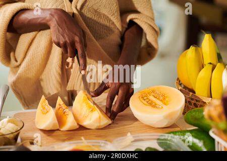 Gros plan image d'une femme coupant du melon en tranches pour servir de dessert Banque D'Images