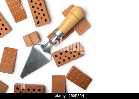 Mini briques céramiques et Trowel matériel de construction et de construction, concept de mur de construction. Isolé sur blanc Banque D'Images