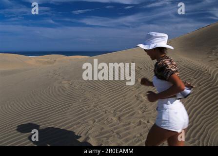 Femme jogging le long des dunes de sable à Playa del Ingles, Gran Canaria, îles Canaries, Espagne Banque D'Images