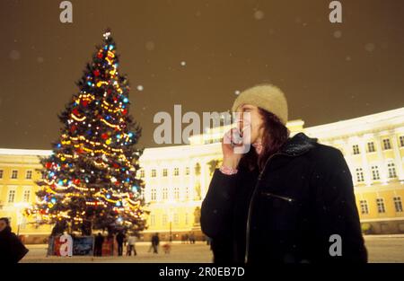 Arbre de Noël et femme avec téléphone cellulaire sur la place du Palais la nuit, St. Petersbourg, Russie, Europe Banque D'Images