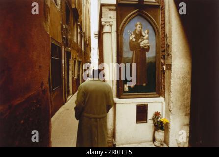 Homme regardant la photo sainte dans la Calle Bembo, Venise, Italie Banque D'Images