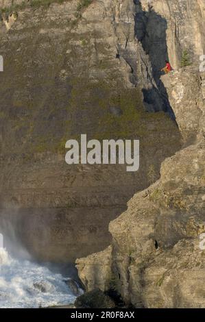 Homme assis sur un rocher au-dessus des chutes de virginie, montagnes Mackenzie, Territoires du Nord-Ouest, Canada Banque D'Images
