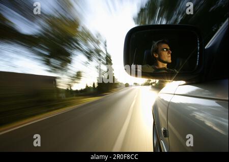 Homme conduisant une automobile, face dans le miroir de conduite, près de Palafrugell, Costa Brava, Catalogne, Espagne Banque D'Images