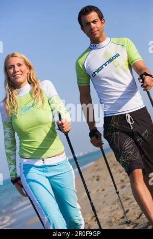 Couple marchant avec des bâtons sur la plage, Apulia, Italie Banque D'Images