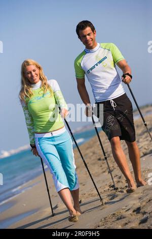 Couple marchant avec des bâtons sur la plage, Apulia, Italie Banque D'Images