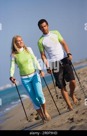 Couple marchant avec des bâtons sur la plage, Apulia, Italie Banque D'Images