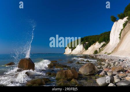 Vagues éclaboussant contre des rochers avec des falaises de craie en arrière-plan, parc national de Jasmund, Mecklembourg-Poméranie occidentale, Allemagne Banque D'Images