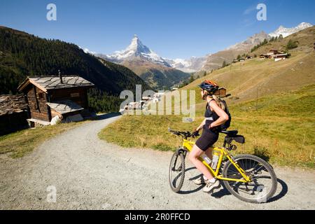 Motard de montagne femelle regardant vers le village de montagne Findeln, Matterhorn, 4478 m, en arrière-plan, Zermatt, Valais, Suisse Banque D'Images