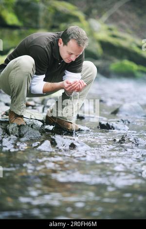 L'homme à partir d'un flux d'eau potable Banque D'Images