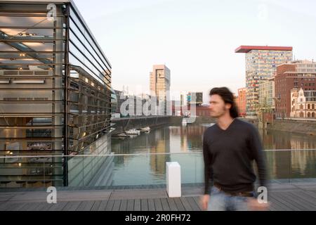 Homme marchant dans le port média de Düsseldorf, immeubles de bureaux modernes en arrière-plan, nouveau quartier de Düsseldorf, capitale de l'État de NRW, Nord R. Banque D'Images