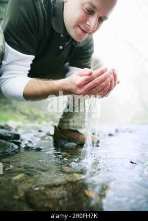 L'homme à partir d'un flux d'eau potable Banque D'Images