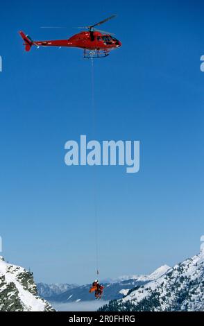 Hélicoptère secourant une personne blessée dans les montagnes, équipe de sauvetage et personne blessée accrochée sur la ligne longue de l'hélicoptère, Hochfuegen, portée de Banque D'Images