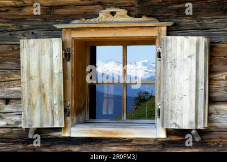 Reflet de montagnes enneigées dans la fenêtre de cabane alpine, Wilder Kaiser Range, Kaiser Range, Tyrol, Autriche Banque D'Images