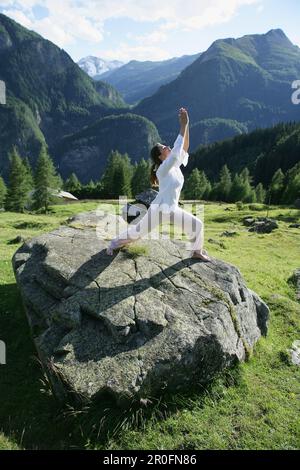Woman practicing yoga on a rock, Heiligenblut, le Parc National du Hohe Tauern, Carinthie, Autriche Banque D'Images