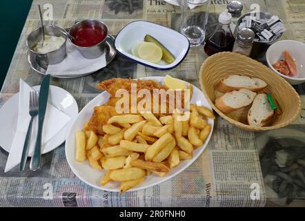 Plie au four avec des frites et une tranche de citron sur l'assiette du restaurant Fish and chips, accompagnée de sauces, de cornichons et de pain Banque D'Images
