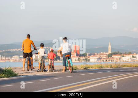 Deux enfants avec leurs parents, cyclistes amateurs, faire une pause et regarder le paysage marin pendant une journée d'été claire Banque D'Images