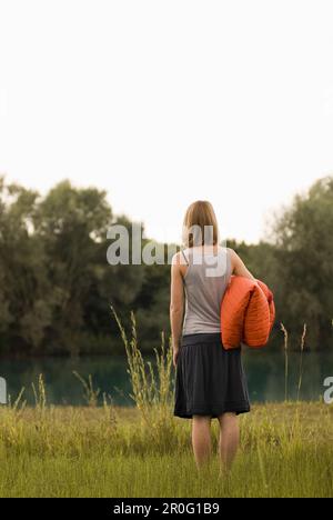 Adolescente tenant une couverture debout à l'étang de carrière, Freising, Bavière, Allemagne Banque D'Images