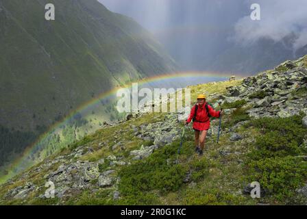 Femme randonnée sous la pluie avec arc-en-ciel au-dessus de la vallée Pfosmental, gamme Texel, gamme Oetztal, Tyrol du Sud, Italie Banque D'Images