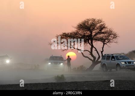 Une personne et trois véhicules tout-terrain devant le soleil couchant, montagnes Al Hajar, Oman, Asie, Oman, Asie Banque D'Images