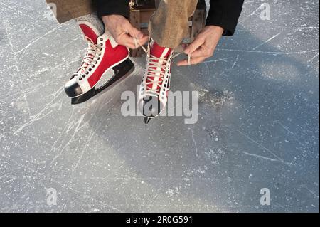 Homme senior qui met sur le patin à glace, lac Ammersee, haute-Bavière, Allemagne Banque D'Images