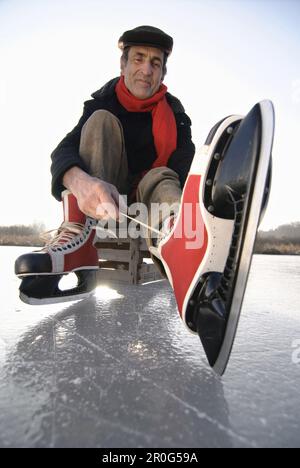 Homme senior qui met sur le patin à glace, lac Ammersee, haute-Bavière, Allemagne Banque D'Images