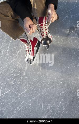 Homme senior qui met sur le patin à glace, lac Ammersee, haute-Bavière, Allemagne Banque D'Images