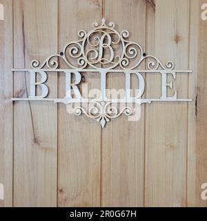 Un panneau en bois avec le mot « mariée » est accroché à la porte de la chambre de la mariée dans un lieu de mariage. Banque D'Images