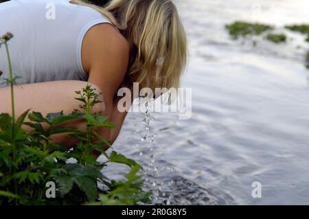 Femme lave son visage à un ruisseau, Bavaria, Germany, Europe Banque D'Images