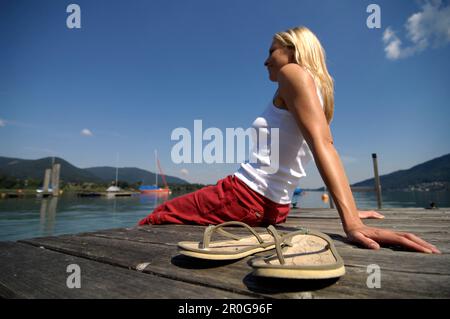 Femme assise sur une jetée en bois, le lac Tegernsee, Upper Bavaria, Bavaria, Germany Banque D'Images