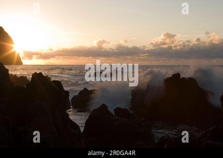 Vague disjoncteur s'écraser sur des roches de lave au coucher du soleil, Porto Moniz, Madeira, Portugal Banque D'Images