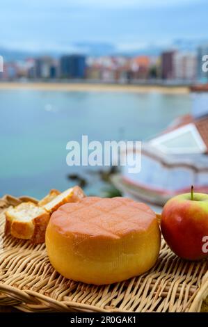 Fromage de vache fumé espagnol de Pria, Asturies, servi en plein air avec vue sur la plage de San Lorenzo et la promenade de Gijon Banque D'Images