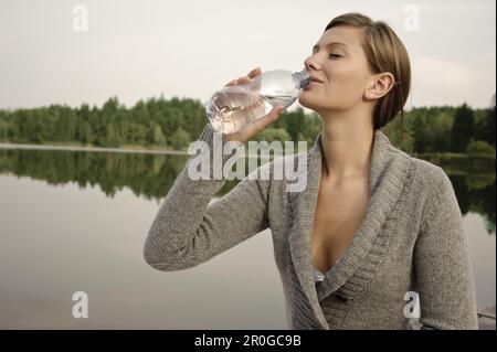 Jeune femme buvant une bouteille d'eau, lac Starnberg, Bavière, Allemagne Banque D'Images