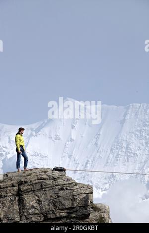Homme debout sur un rocher à haute altitude, Schilthorn, Oberland bernois, canton de Berne, Suisse Banque D'Images