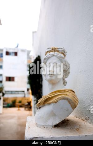 Buste antique de tête de femme contre le mur gris. Statue historique en robe dorée. Visage de femme antique sur fond clair. Photo de haute qualité Banque D'Images