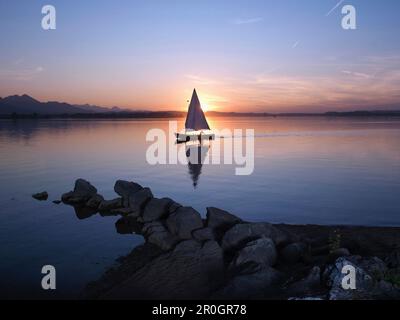 Voilier sur le lac Chiemsee au coucher du soleil, Chiemgau, Bavière, Allemagne Banque D'Images
